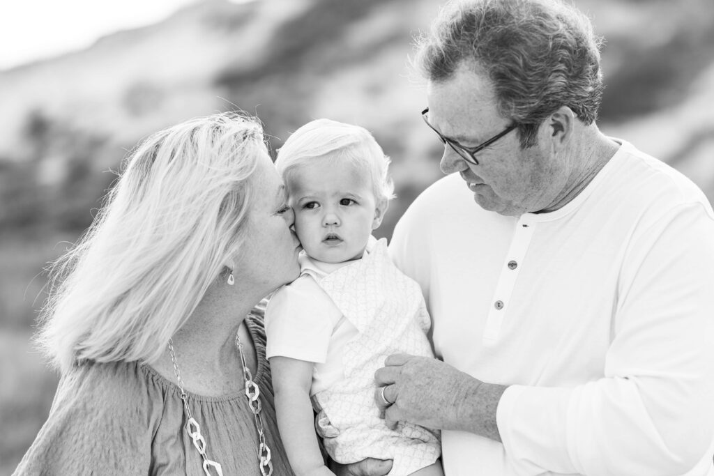 Grandparents holding their grandchild during sunset beach family photos in Jacksonville Beach, Florida